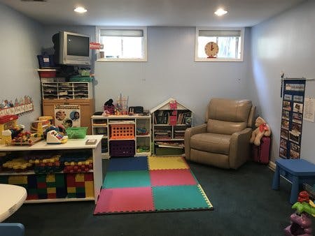 Playroom with colorful floor mats, shelves of toys, and a recliner
