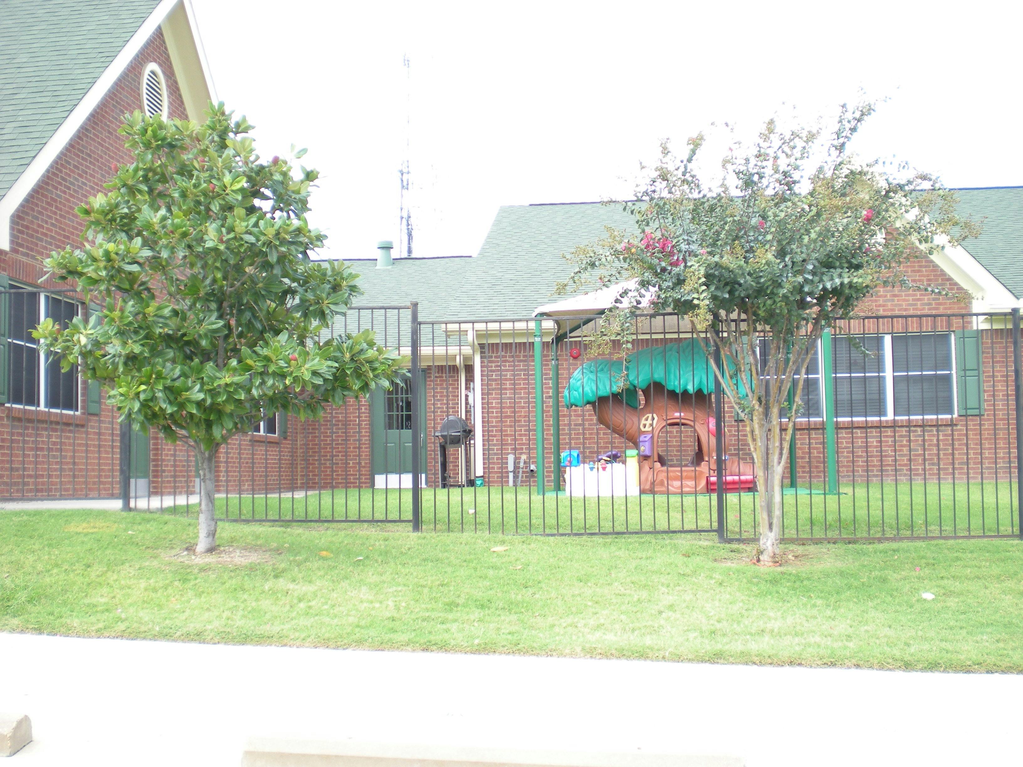 Building exterior with fenced playground area and trees