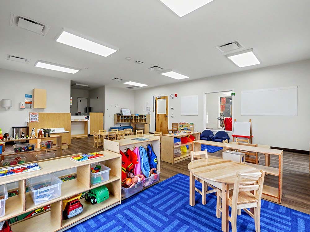 Classroom with child-sized furniture and shelves filled with toys and art supplies