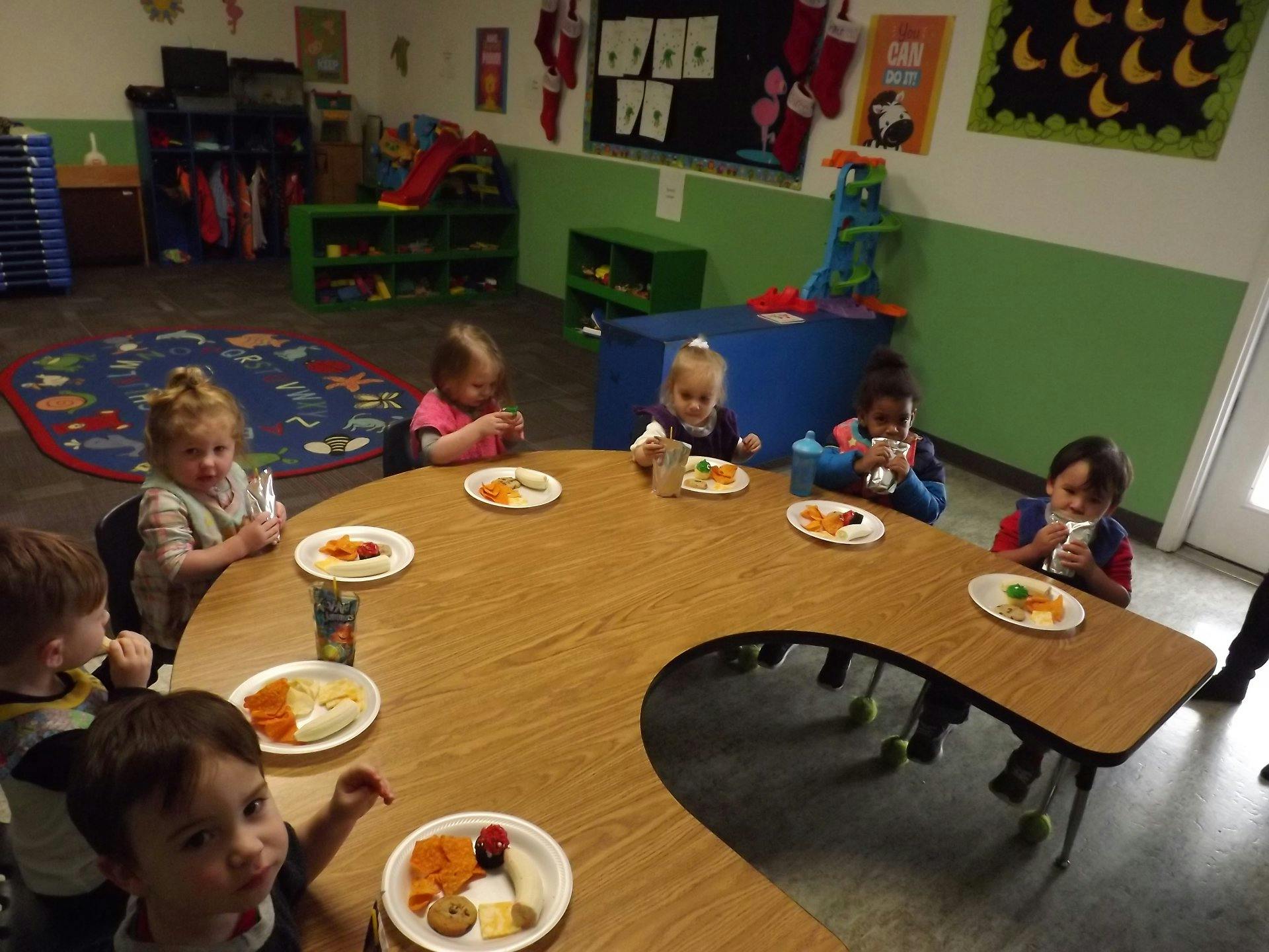 Children eating at a table in a classroom