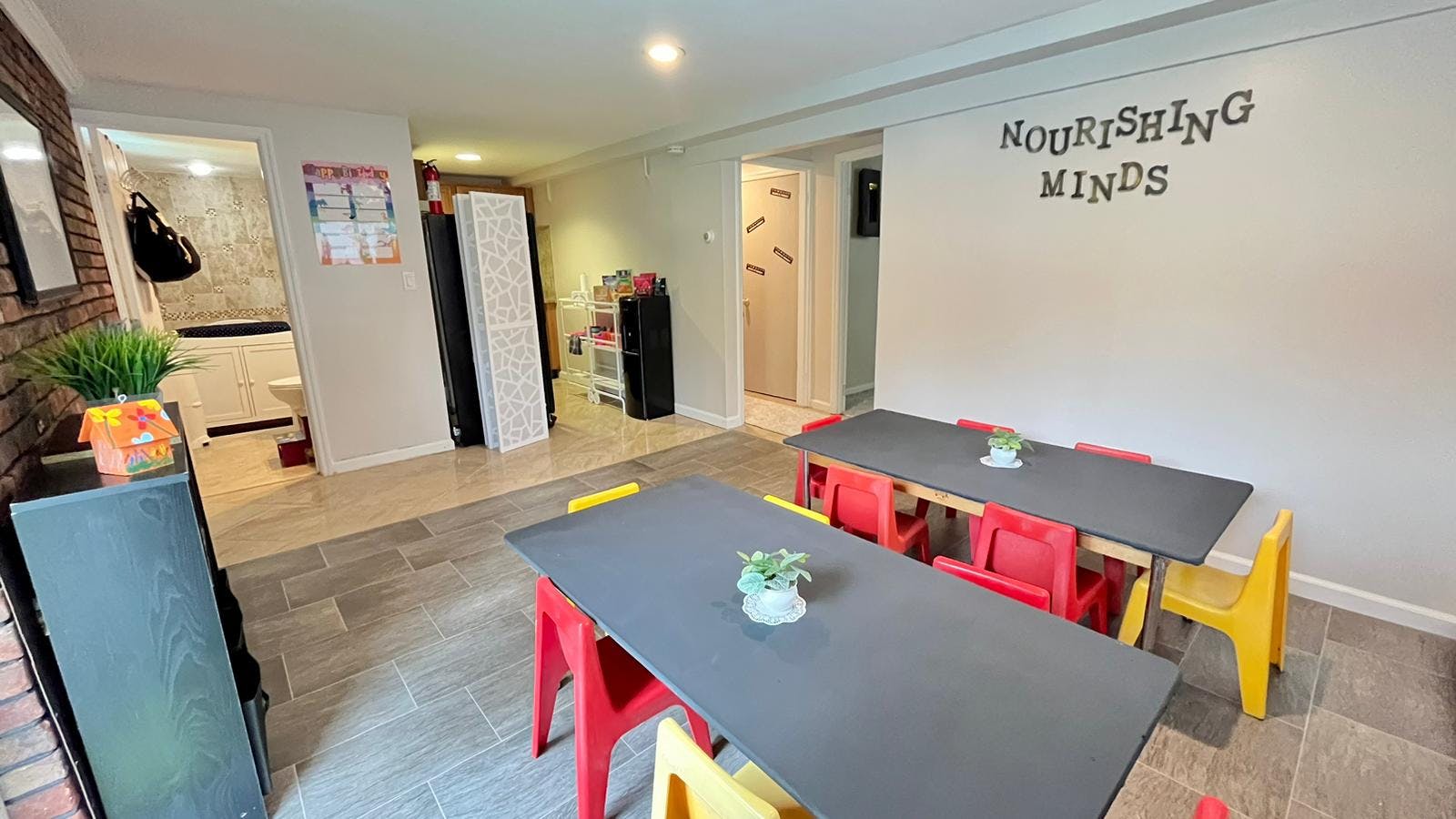 Two tables with red and yellow chairs in a room with "Nourishing Minds" on wall