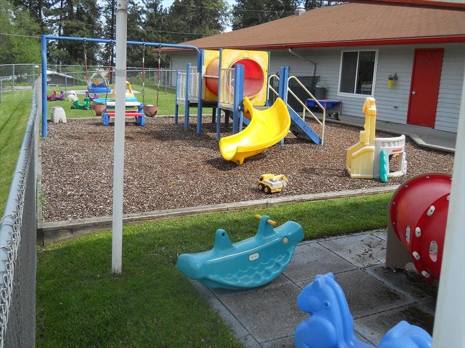 A colorful playground with swings, a yellow slide, and a blue rocking toy