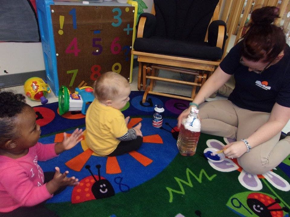 Adult and two children playing on a colorful rug