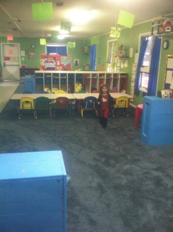 Child walking in a classroom with tables and chairs