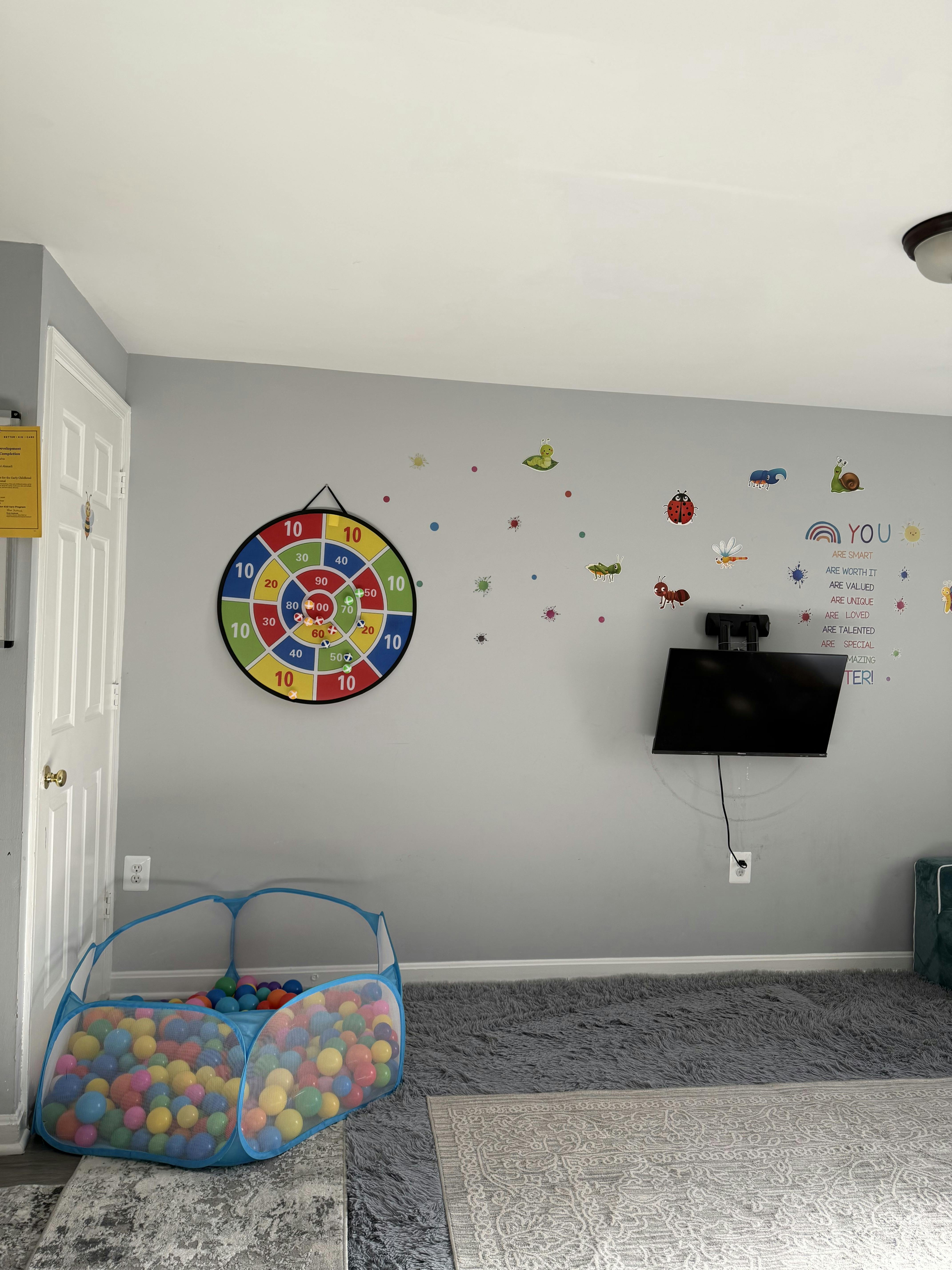 Playroom with a ball pit, dartboard, wall decals, and mounted TV