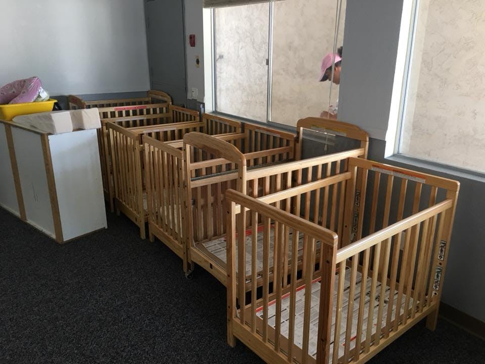 Multiple wooden cribs in a row next to a window