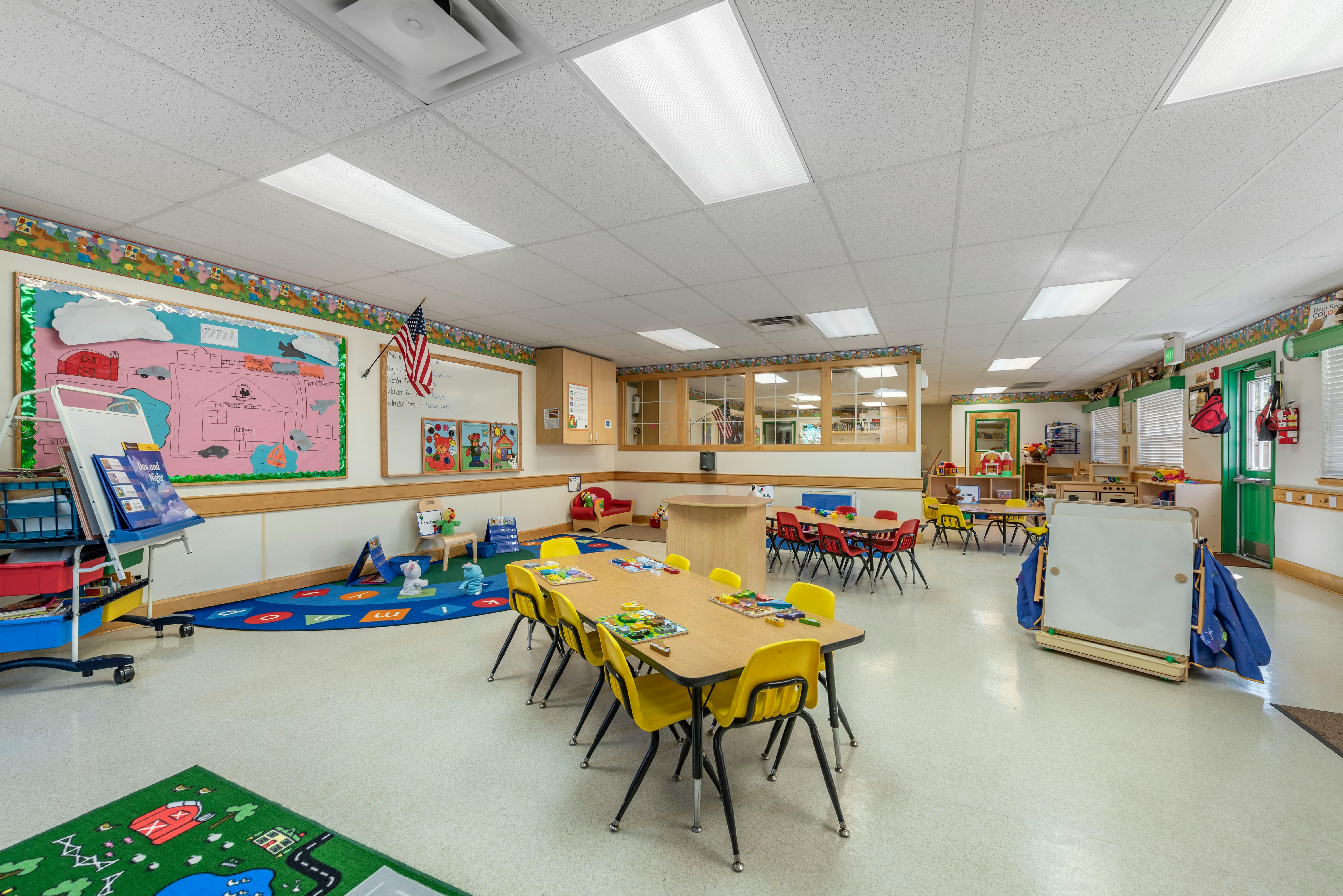 An empty early childhood classroom with small tables and chairs