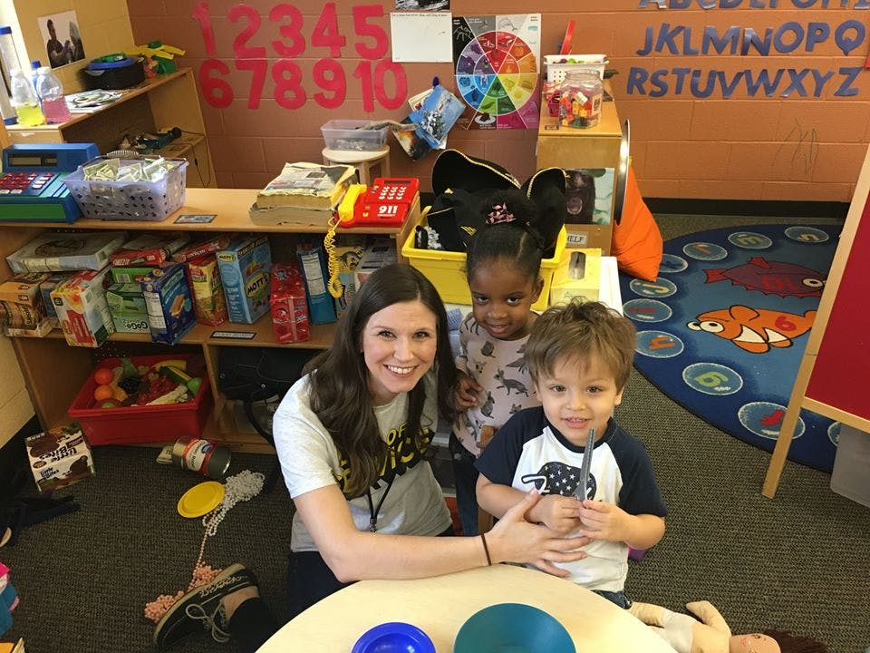 Person with two children in a classroom