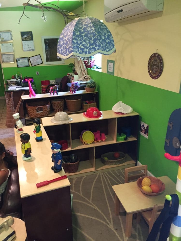 Classroom with shelves of toys and a small table with a fruit bowl