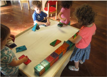 Children playing with colorful magnetic blocks at a table