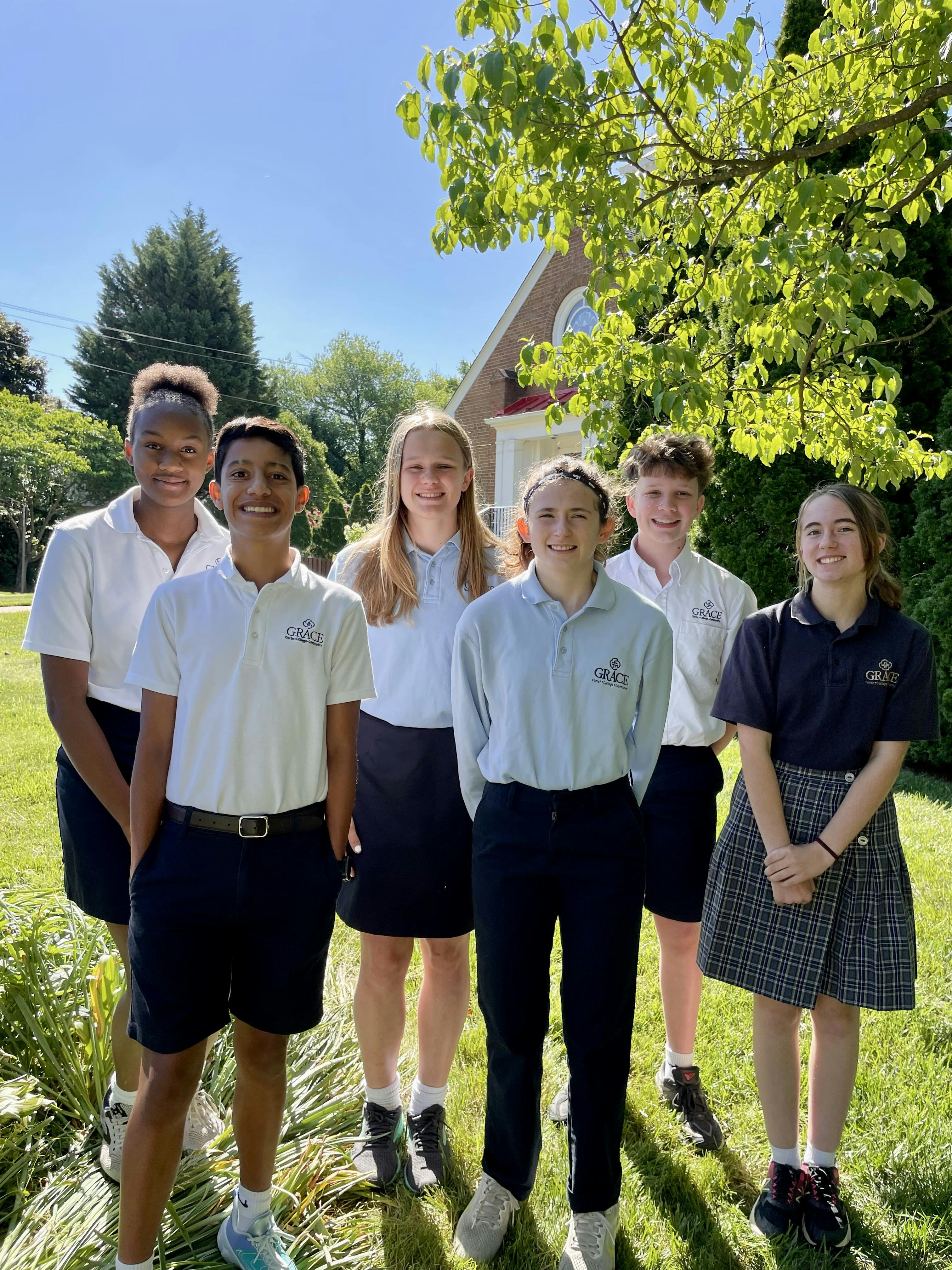 Six teens standing outdoors in uniform