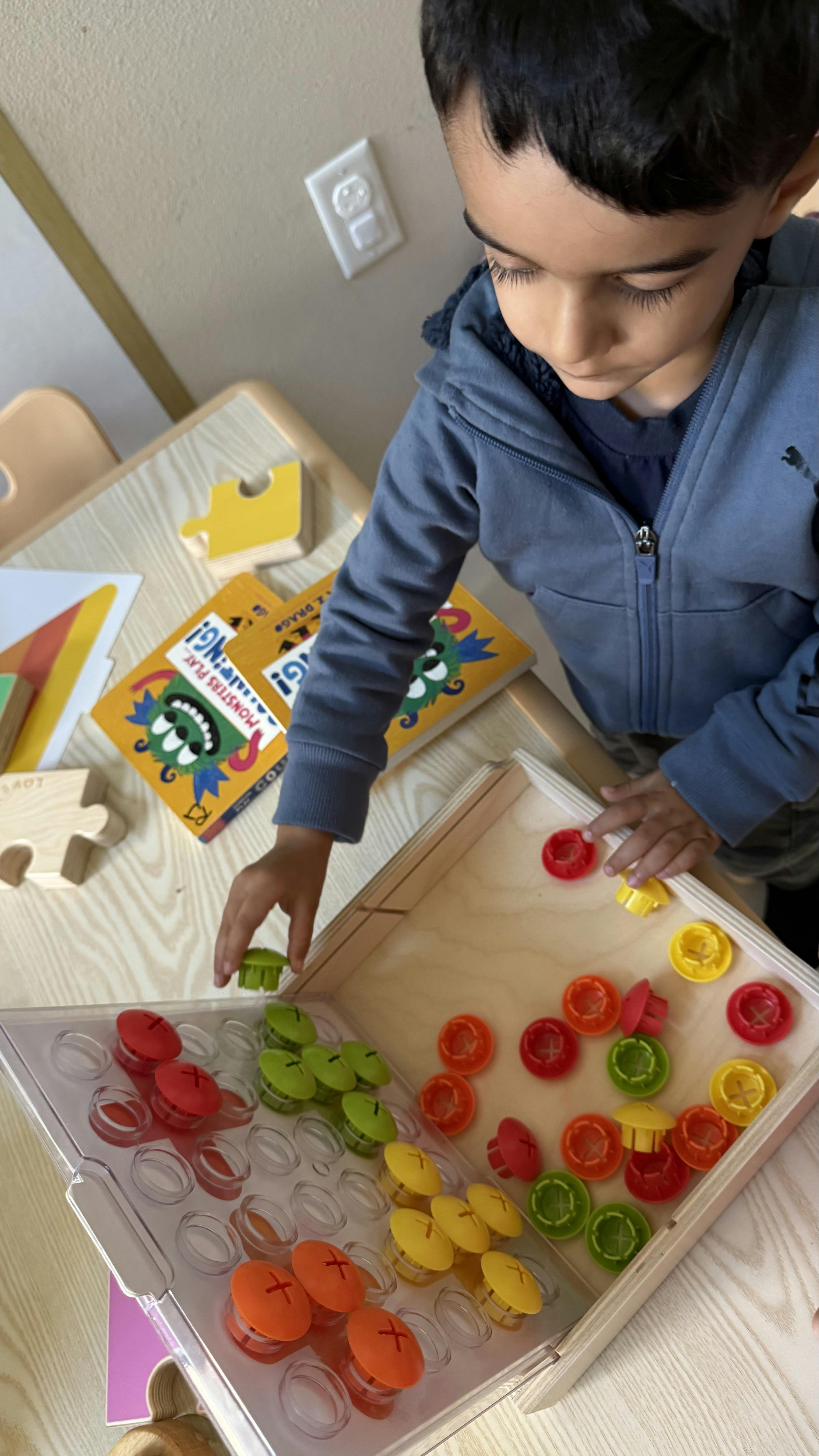 Child playing with colorful sorting game pieces on a wooden table