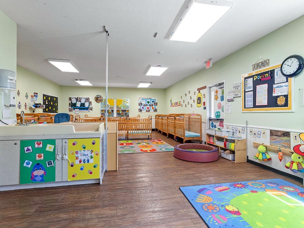 daycare classroom with multiple cribs, changing station, and play mats