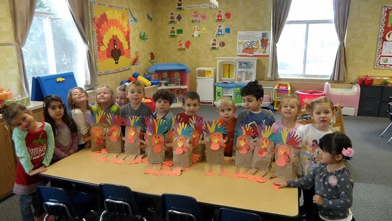 Children standing around a table with crafts in a classroom