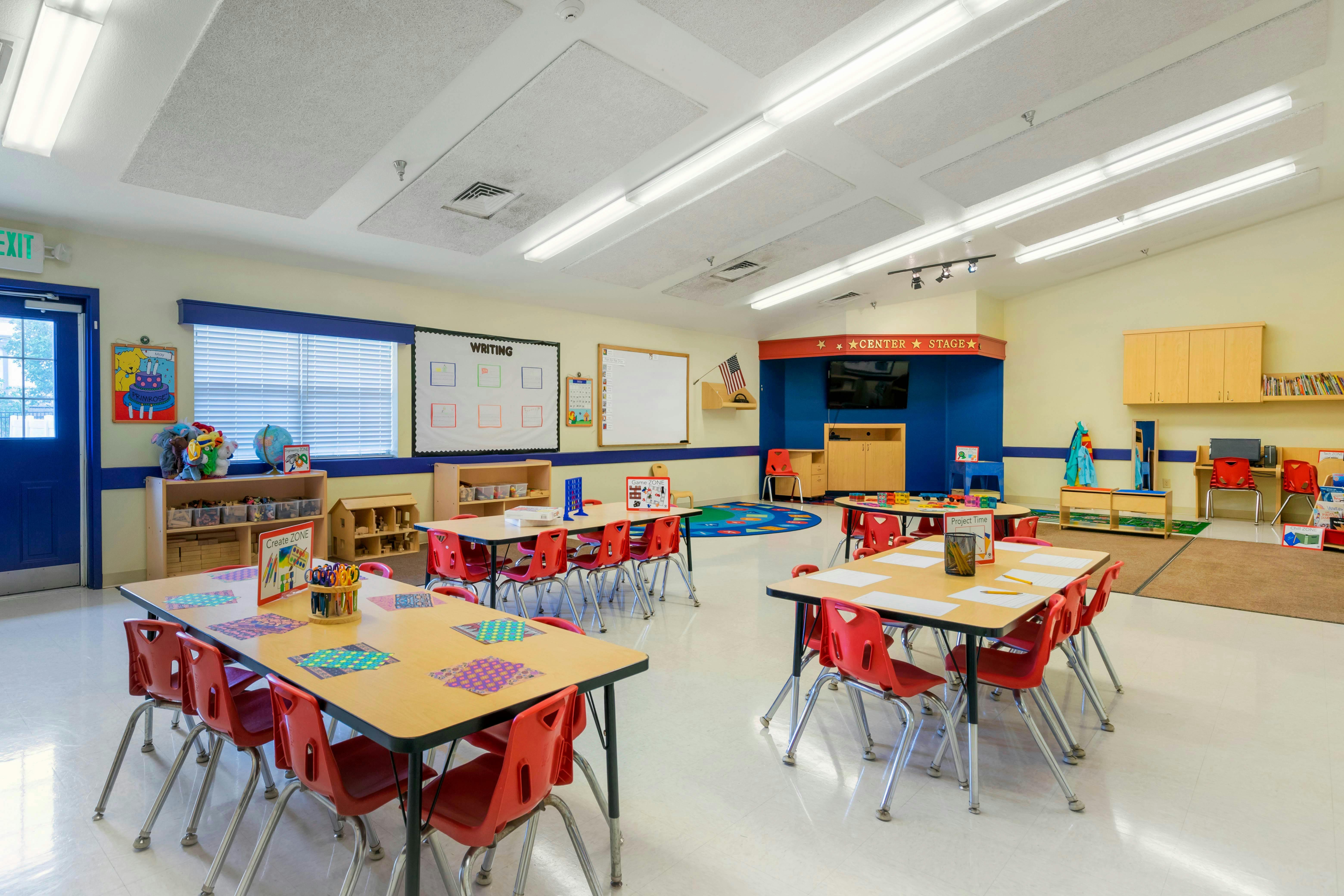 Empty classroom with small tables and red chairs, a "Center Stage" area