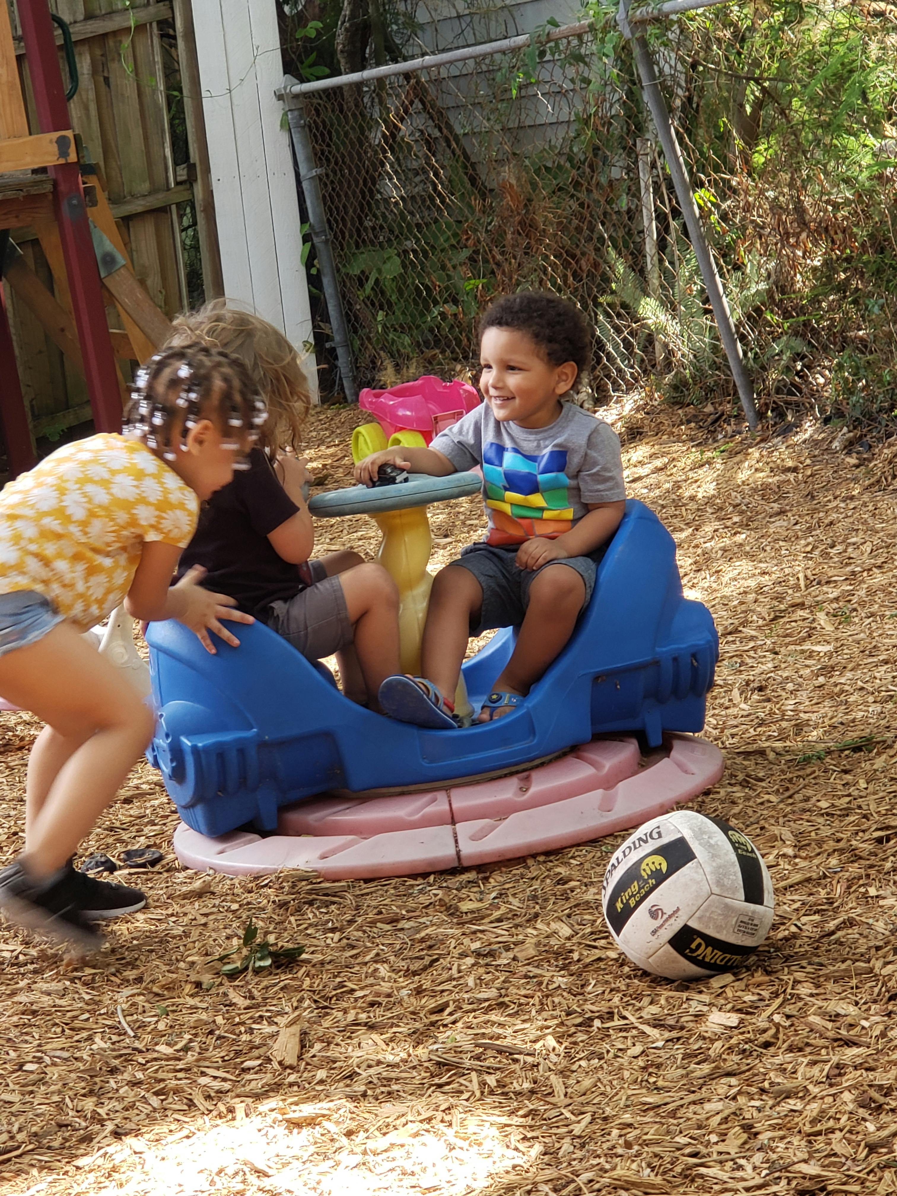 Two children playing on a blue and pink seesaw toy
