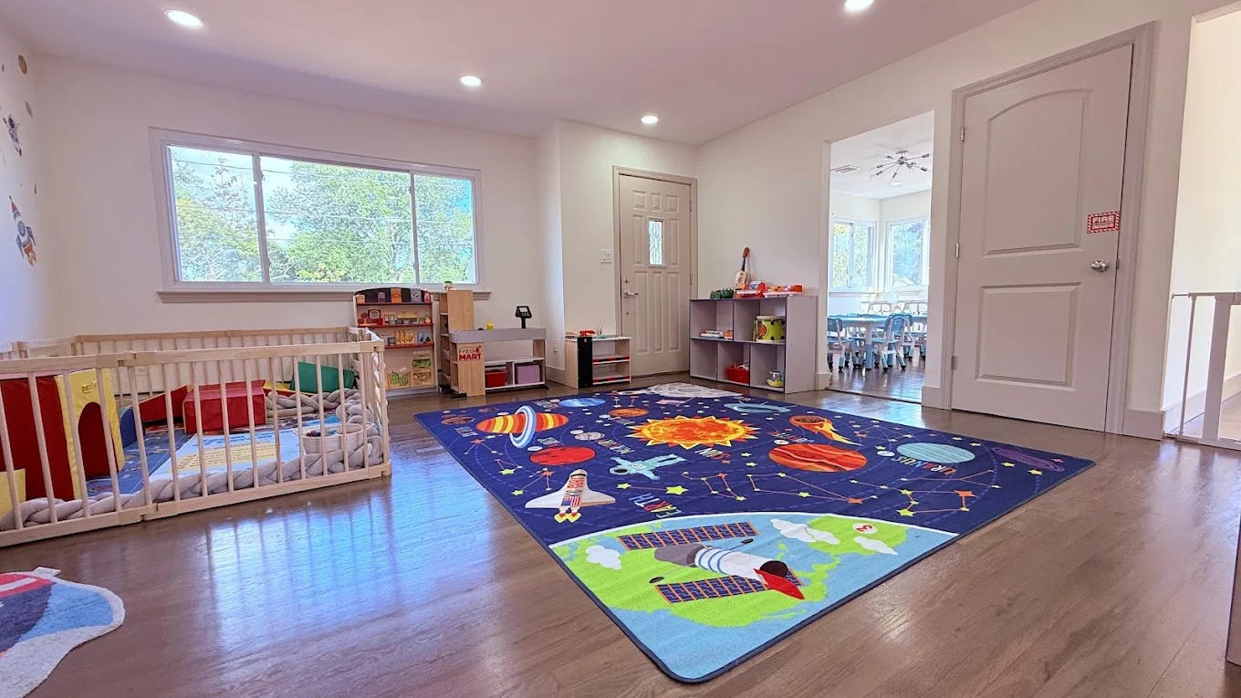 Playroom with a crib, a colorful rug, and a large window