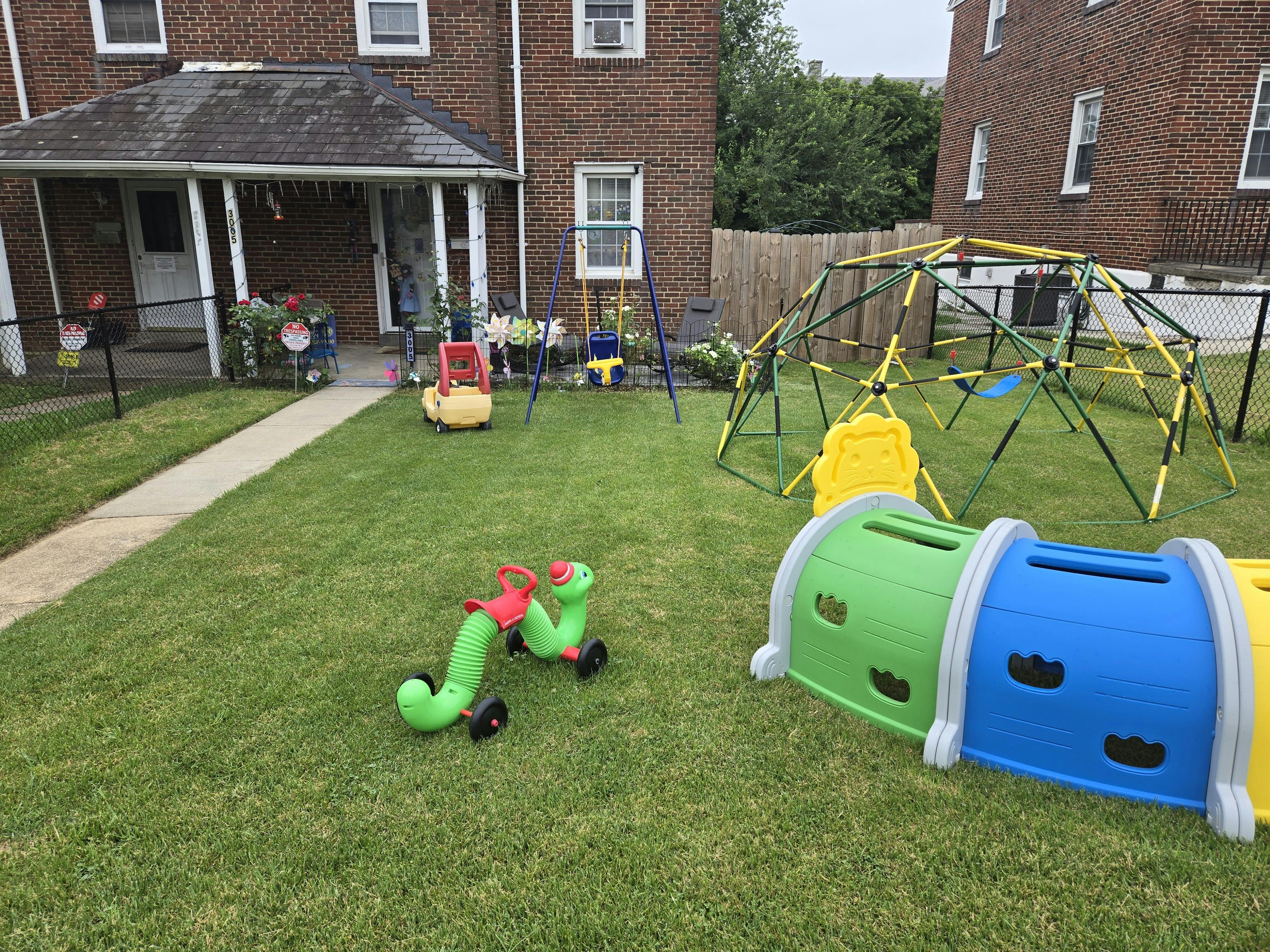 Playground equipment on a lawn in front of a brick building