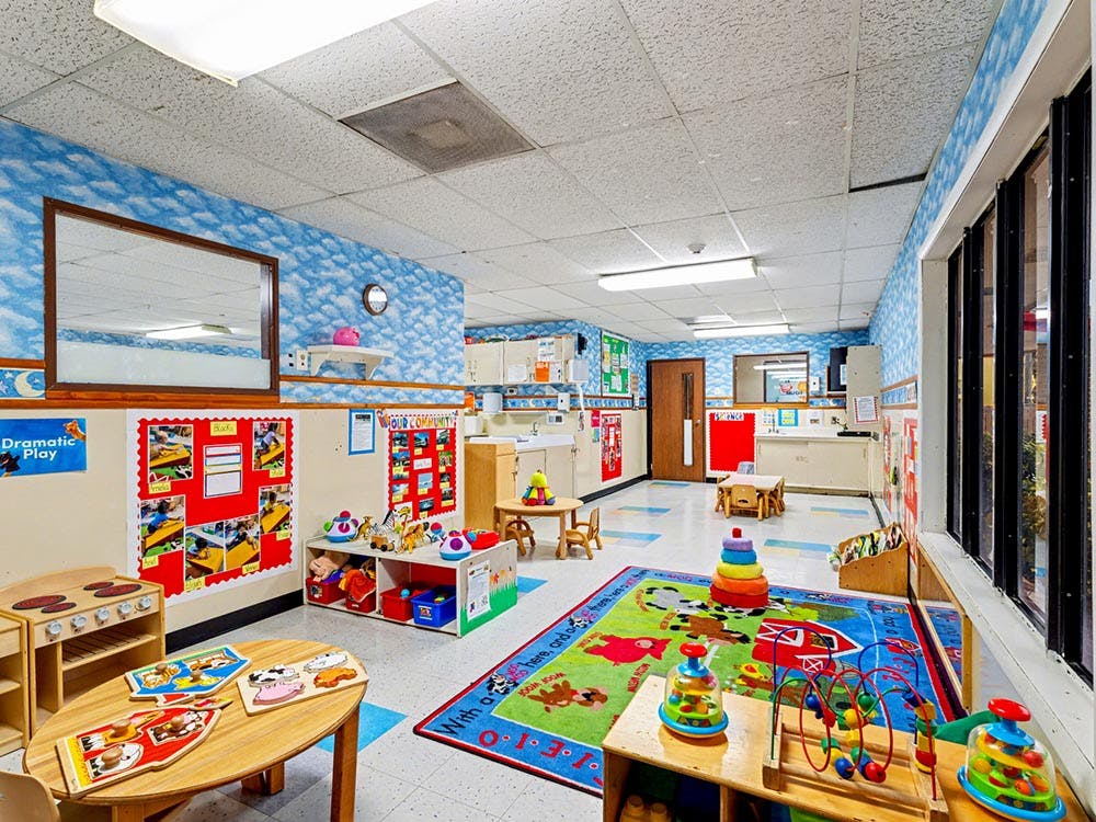 Colorful empty classroom with toys, small tables, and cloud-patterned walls