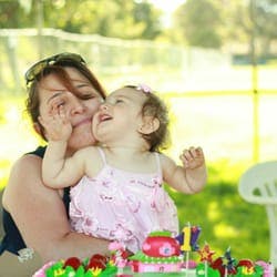 Person holding a child next to a birthday cake