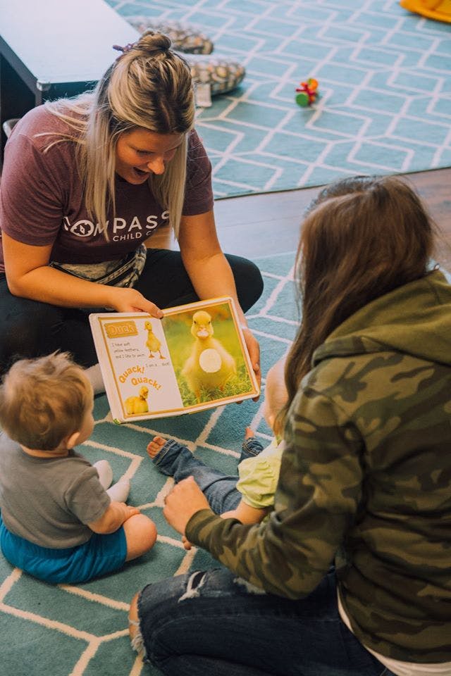 Person reading a book with a duck illustration to two children
