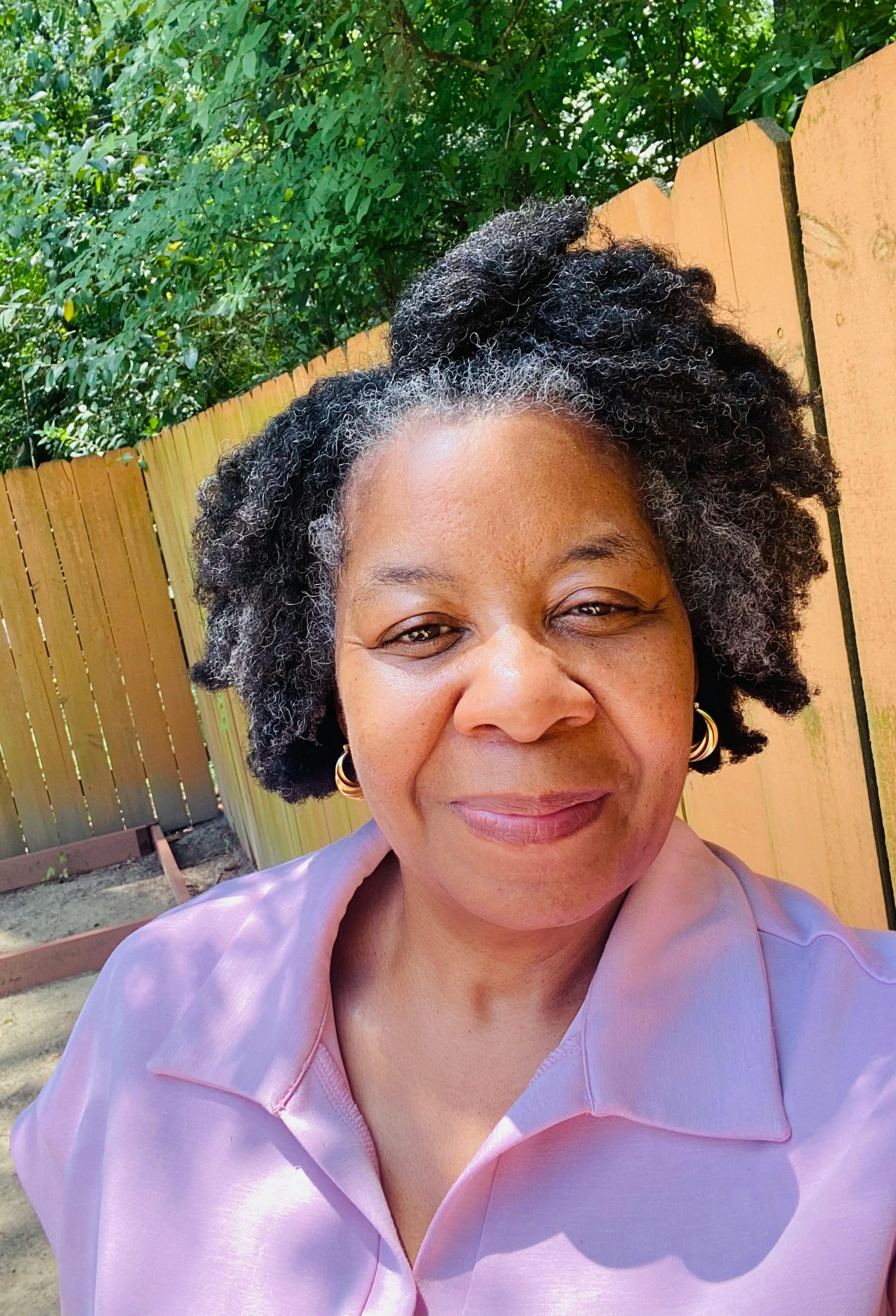Person with curly gray hair and hoop earrings
