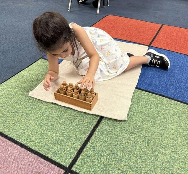 Child lying on a mat playing with wooden cylinder blocks