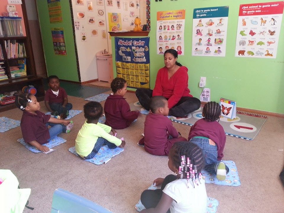Adult and children sitting on floor in classroom