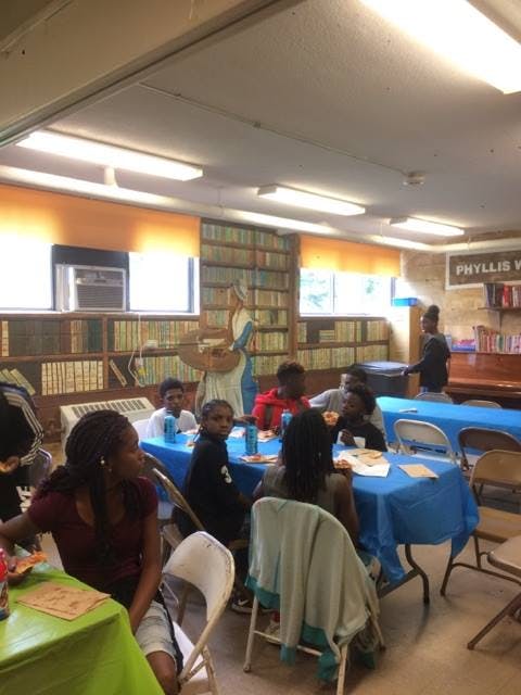 People sitting at tables in a room with bookshelves