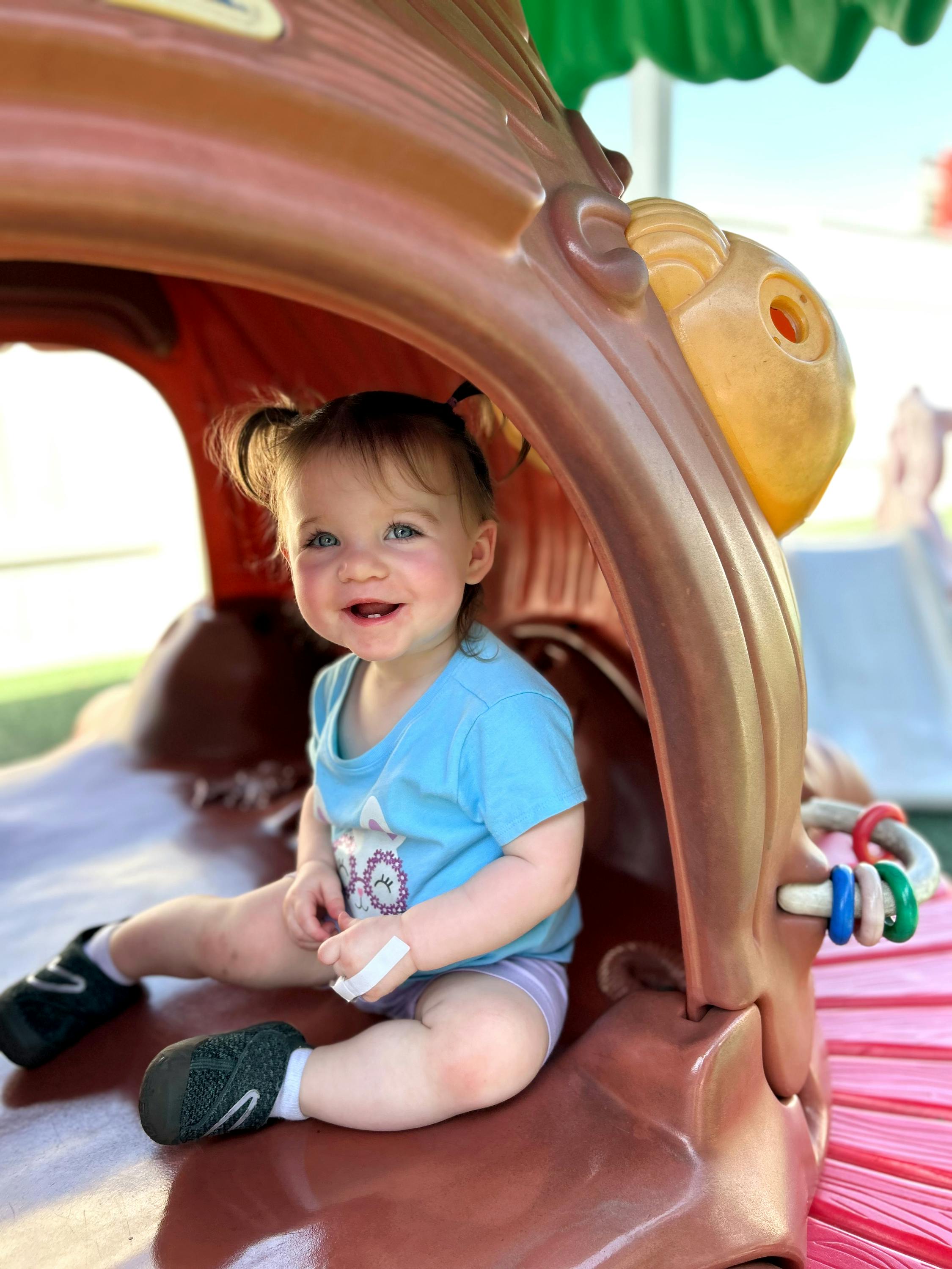 Child with pigtails sitting in a play structure