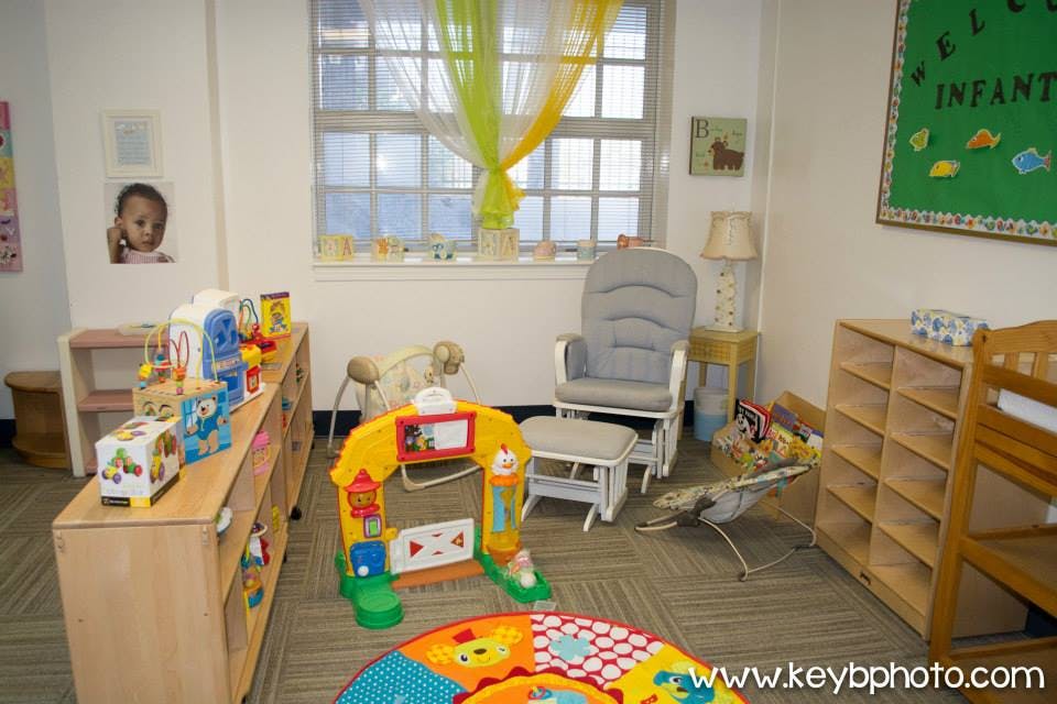 Infant classroom with toys, rocking chair, and play mat