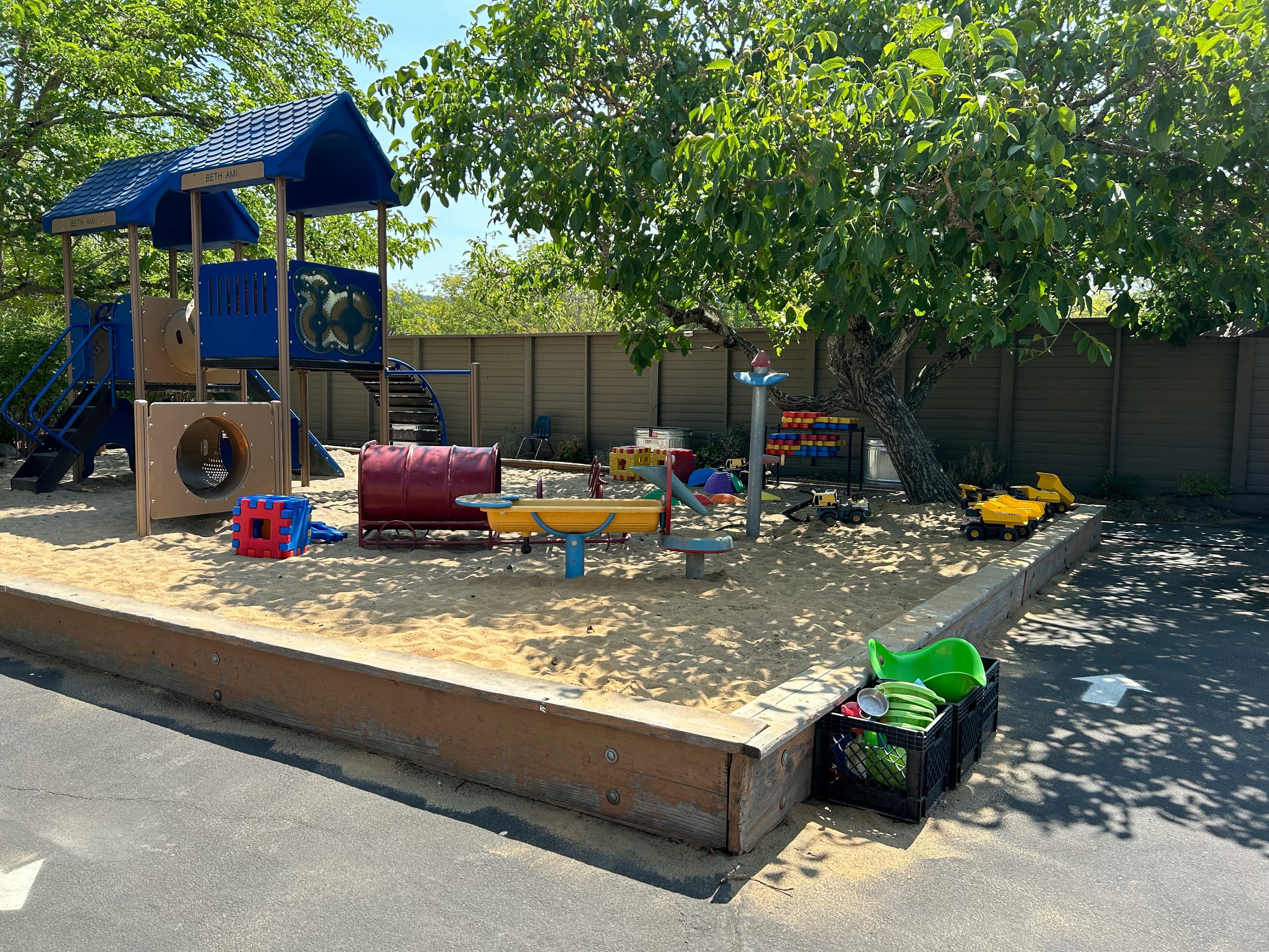 Outdoor playground with sand, play structure, and toys