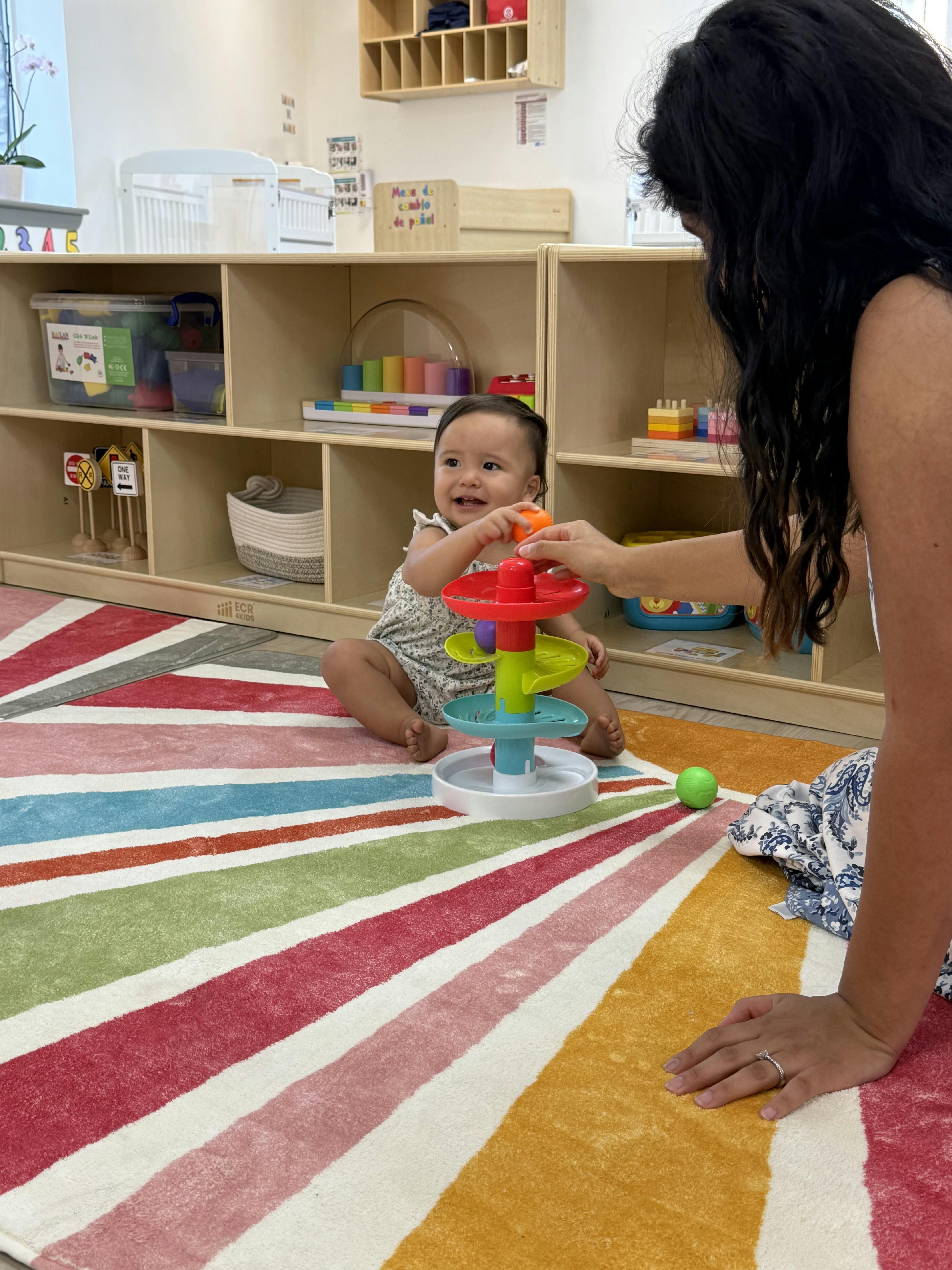 Person and child playing with a colorful toy on a striped rug