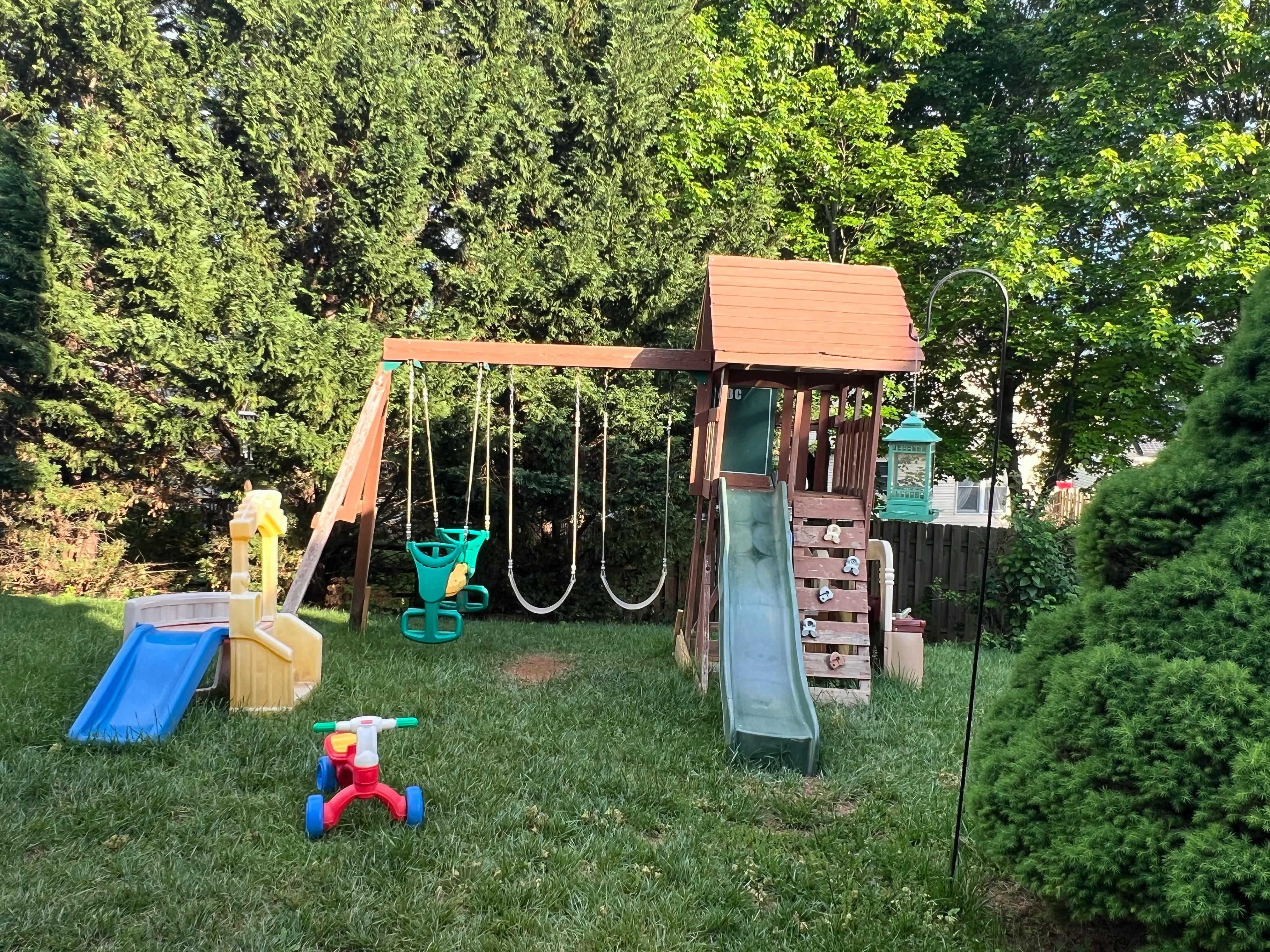 Wooden playset with swings and slides in a grassy yard