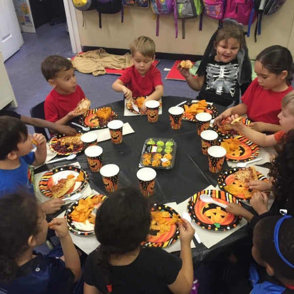 Children eating at a table with Halloween-themed plates and cups