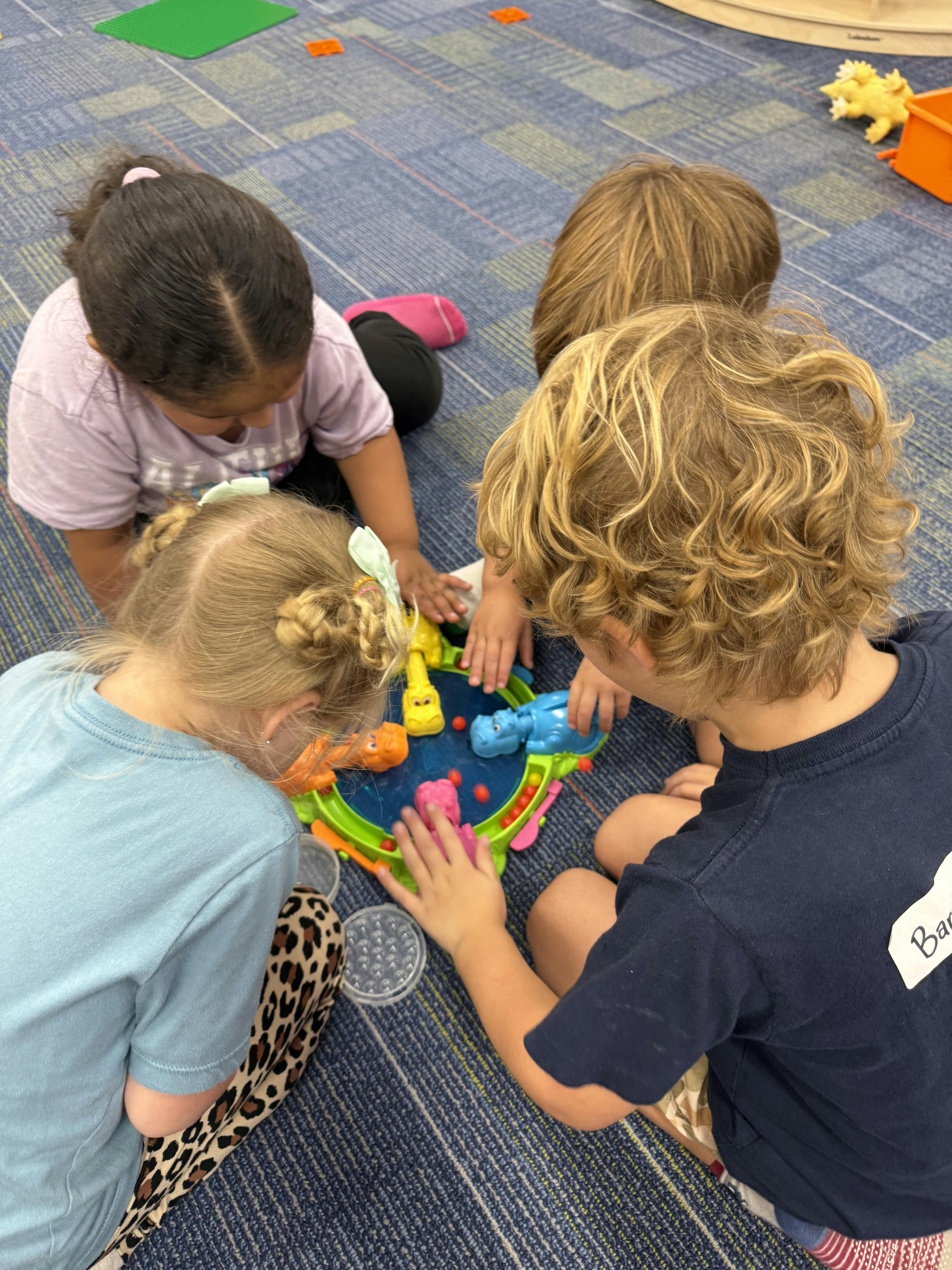 Three children playing a board game on the floor