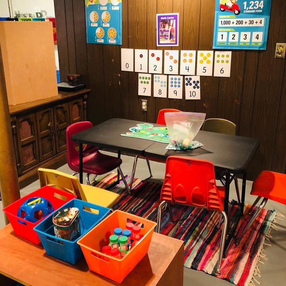 Classroom with a table, chairs, and educational posters on the wall