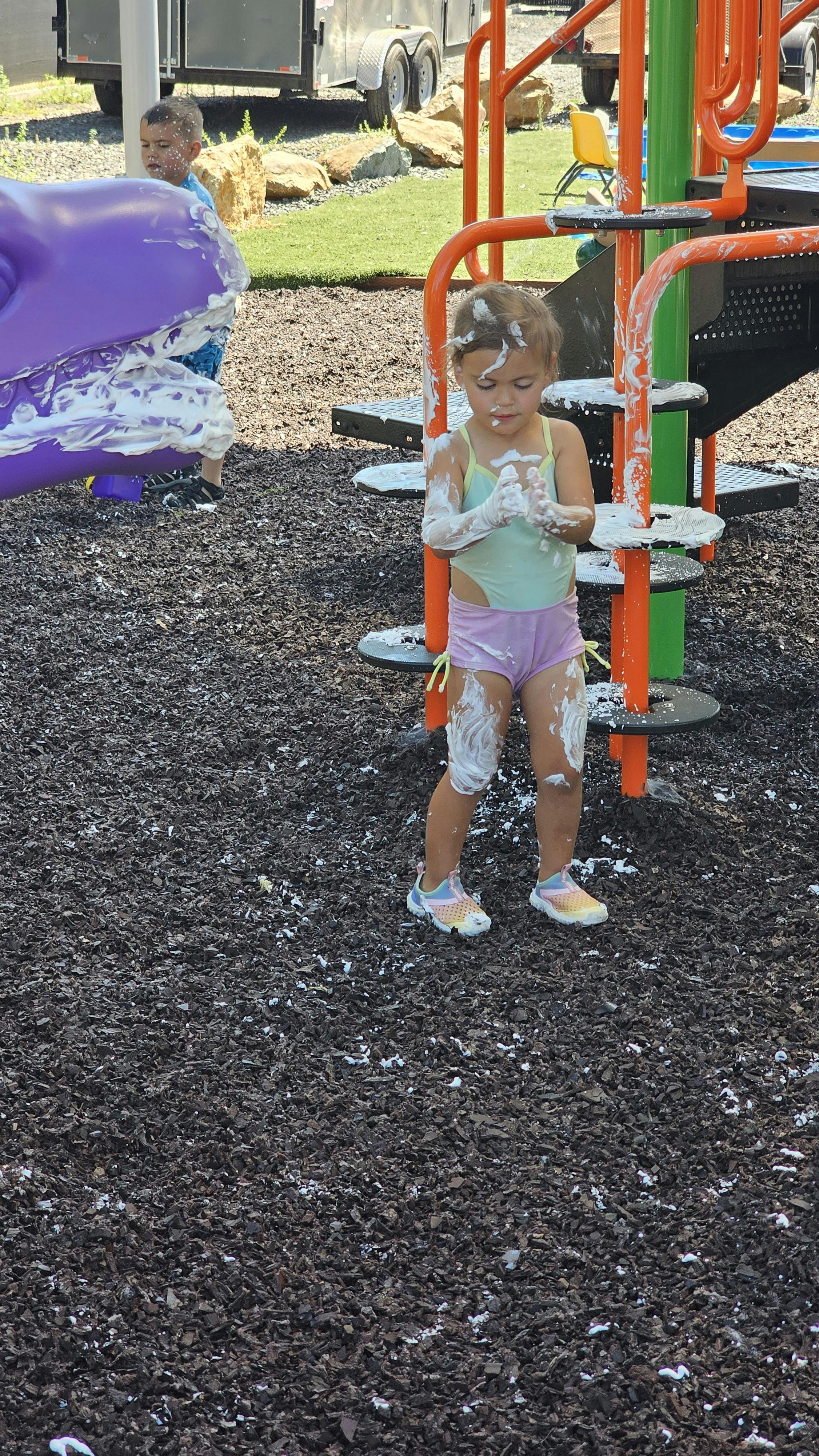 Child covered in white foam on a playground