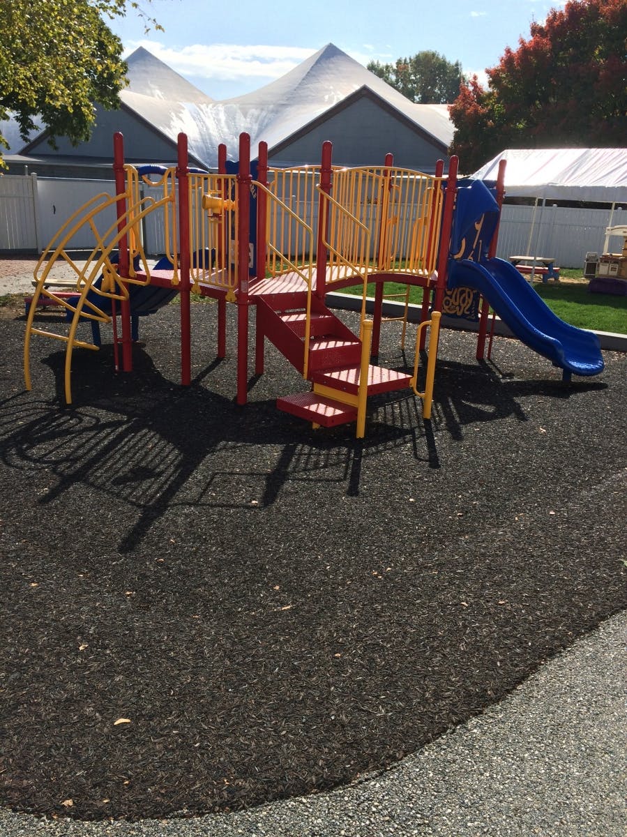 Playground structure with slides and stairs on a rubberized surface