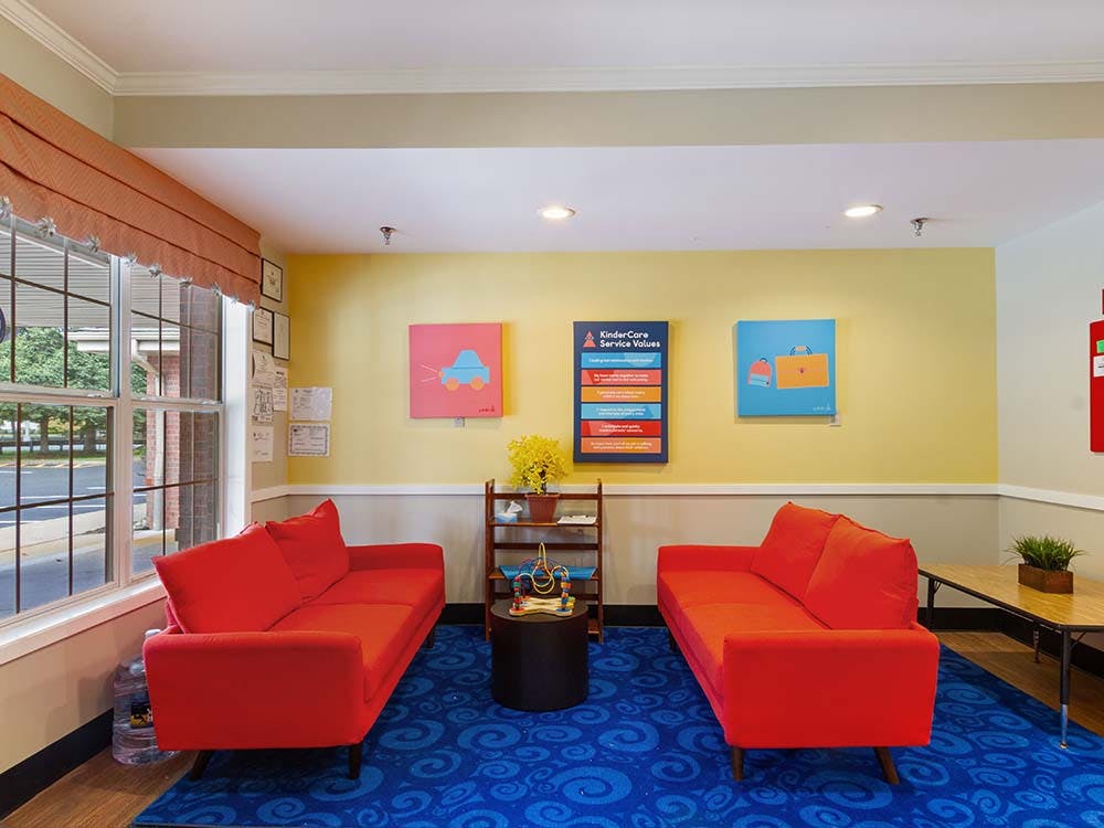 Lobby with two red couches facing each other and KinderCare Service Values sign