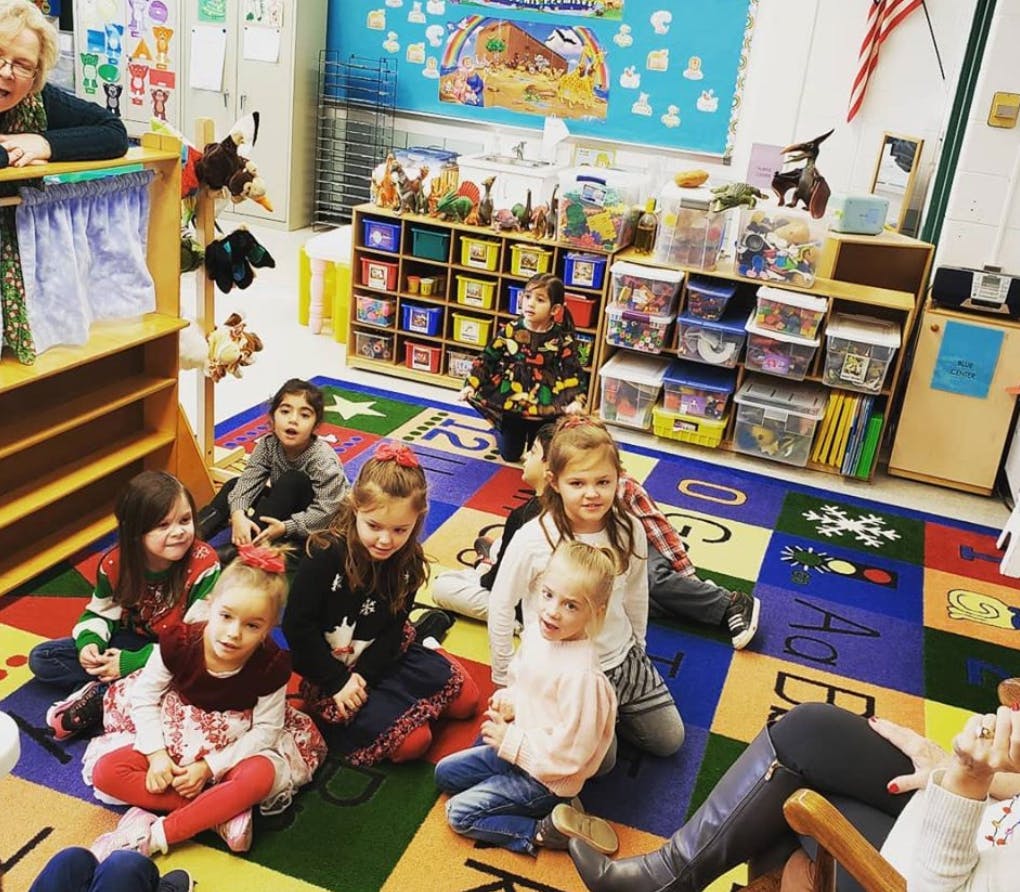 Children sitting on a colorful rug in a classroom