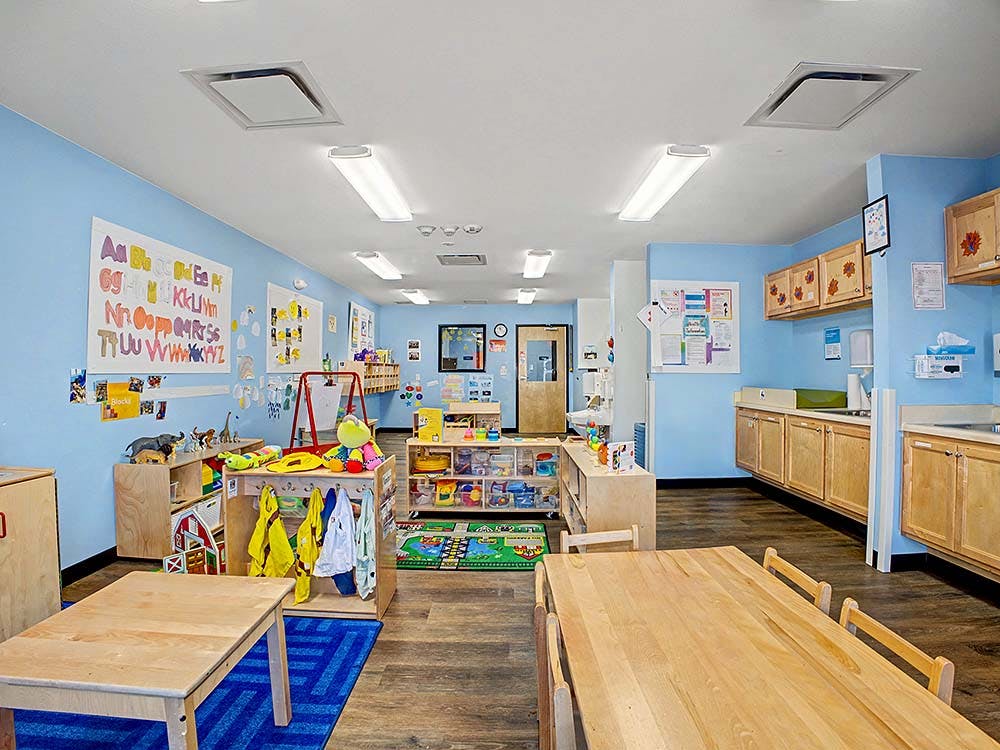 A colorful classroom with tables, alphabet charts, and toys
