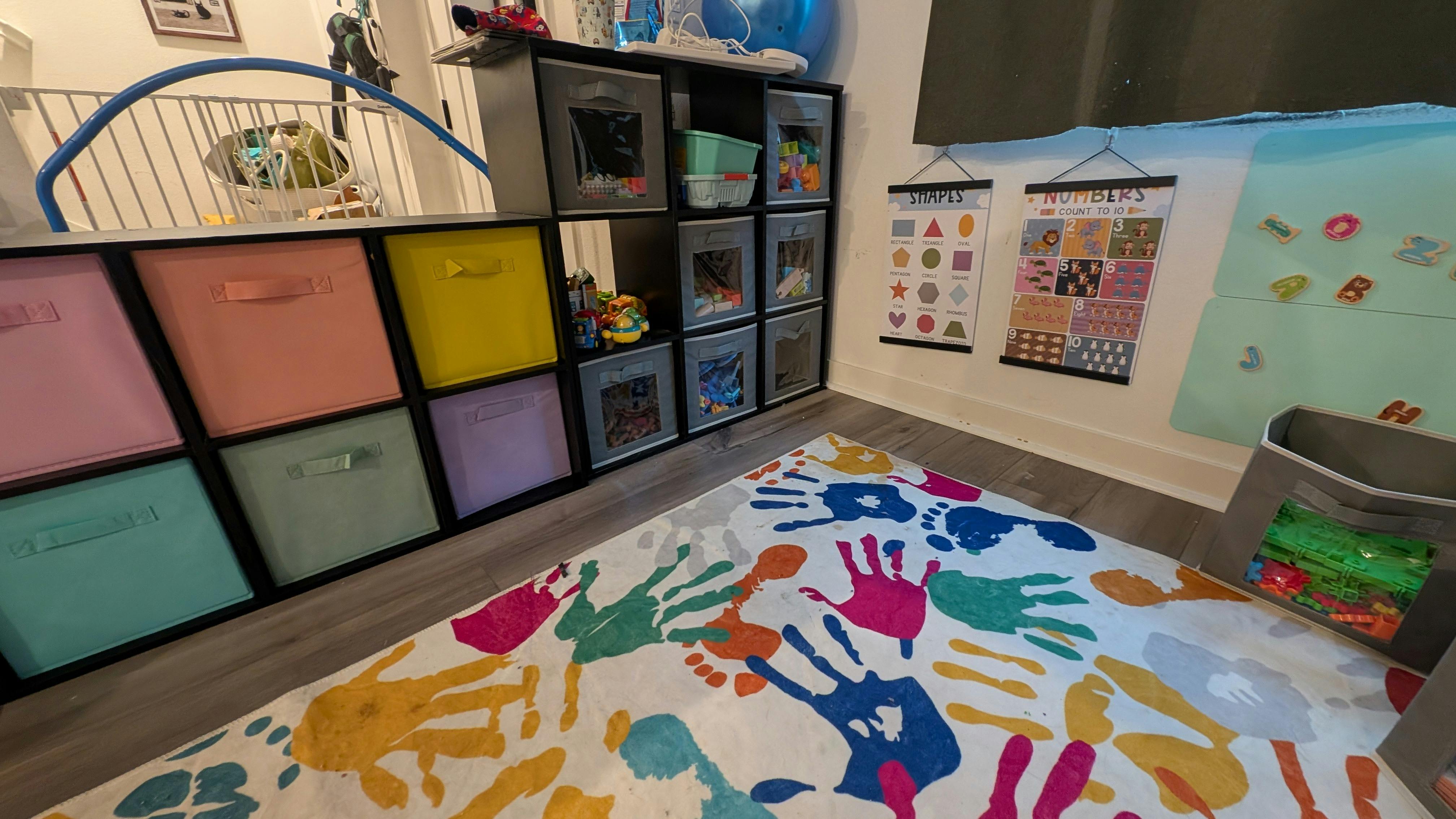 Playroom with colorful rug, storage bins, and wall charts