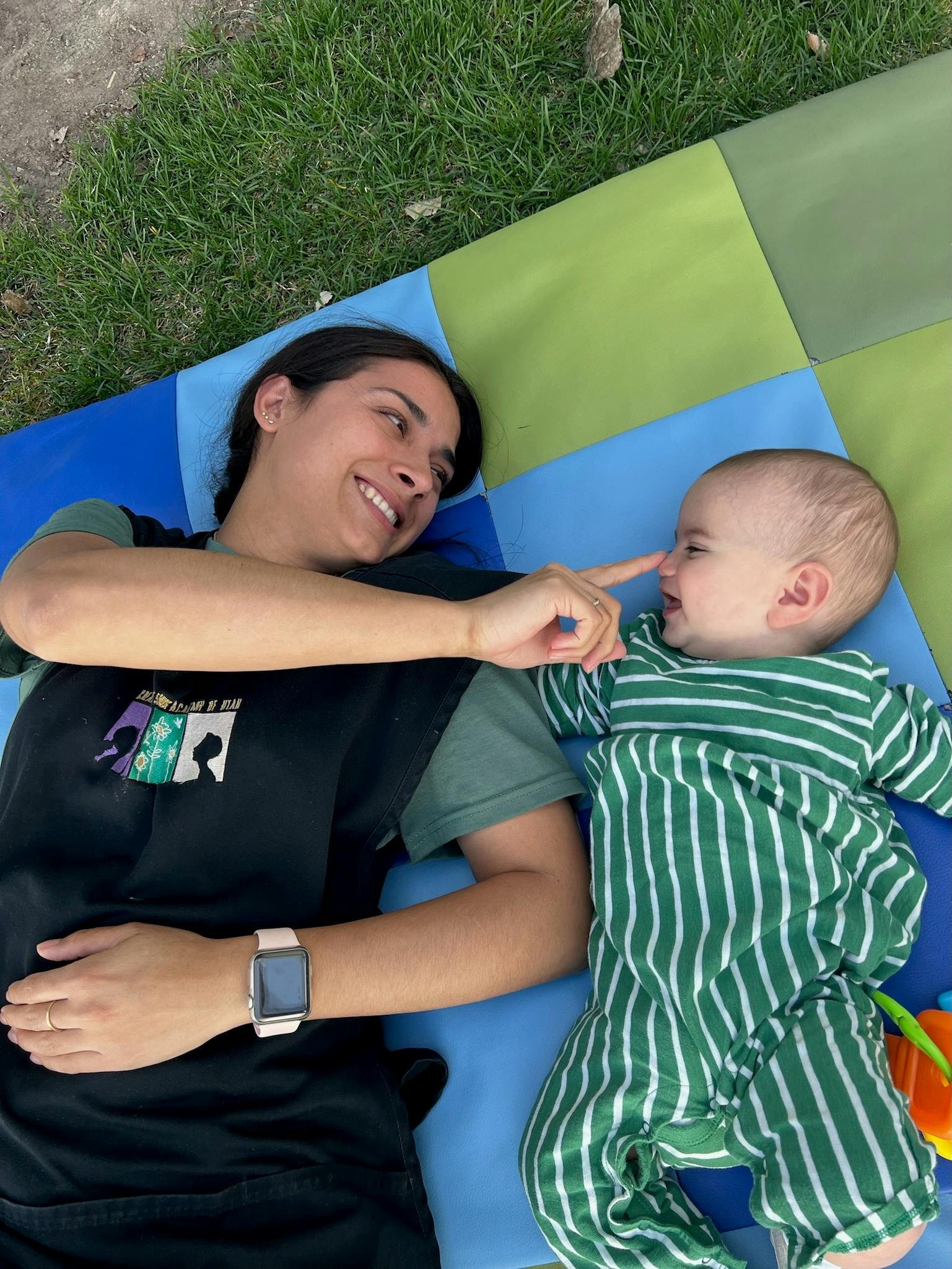 Person and child lying on a blanket, person touching child's nose