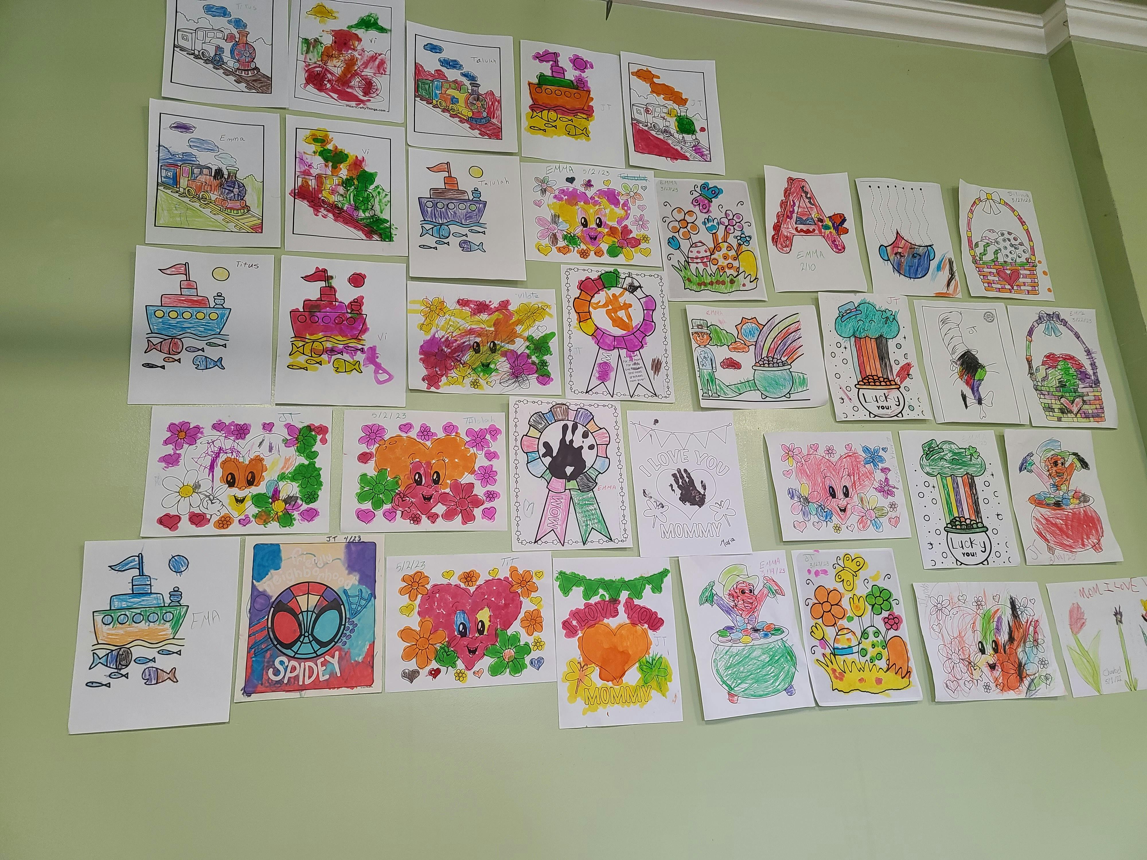Collection of children's drawings displayed on a wall
