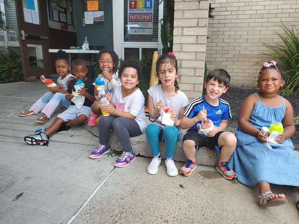 Group of children sitting on a curb holding drinks and snacks