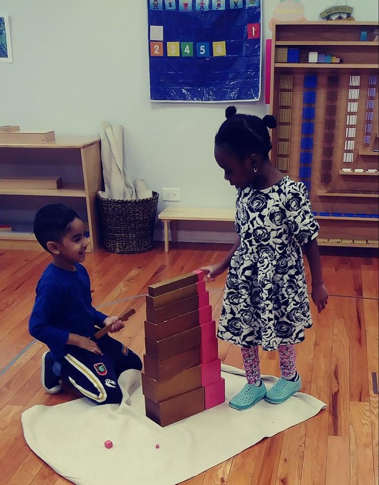 Two children playing with wooden blocks in a classroom