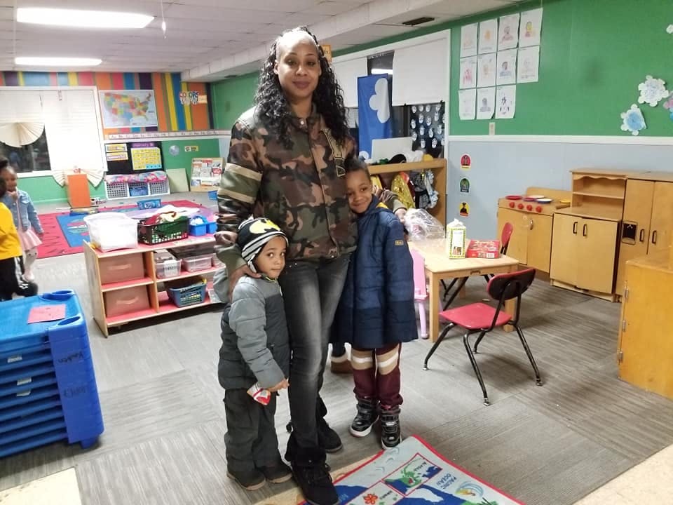 Person standing with two children in a classroom