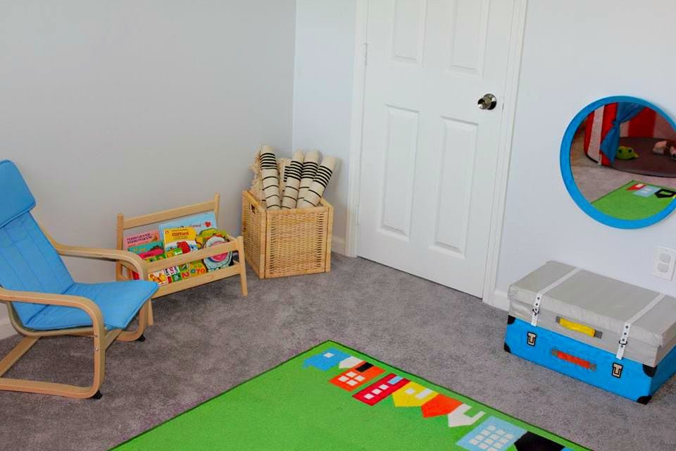 Child's room with a blue chair, bookshelf, and green rug