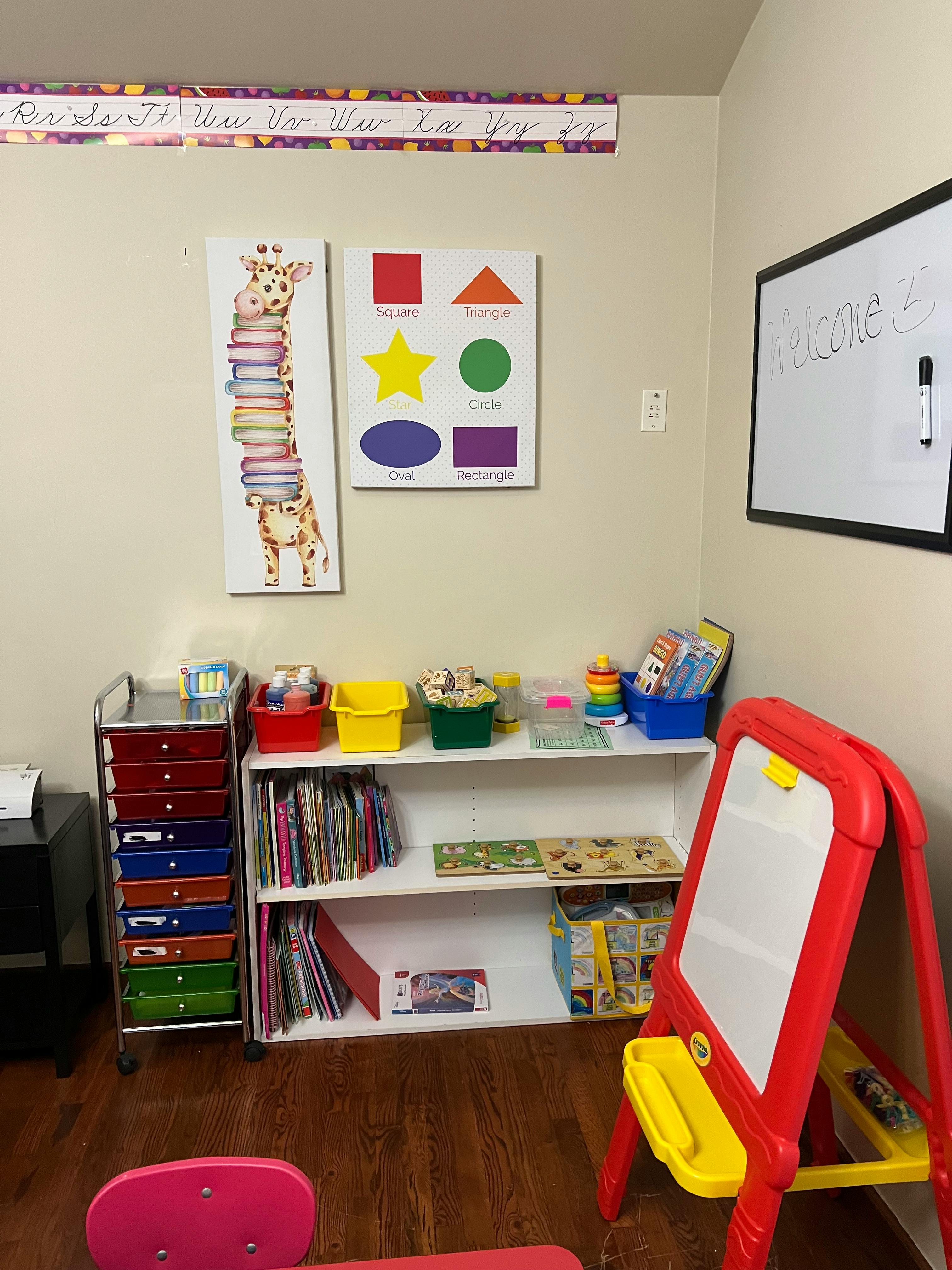 Classroom with a whiteboard, shelves of books, and a red easel